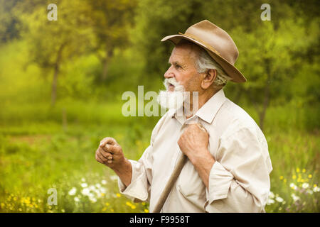 Vieux fermier avec barbe, travailler avec le râteau à jardin Banque D'Images