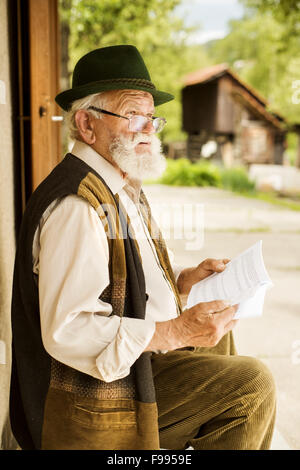 Vieil homme lisant le journal devant sa maison Banque D'Images