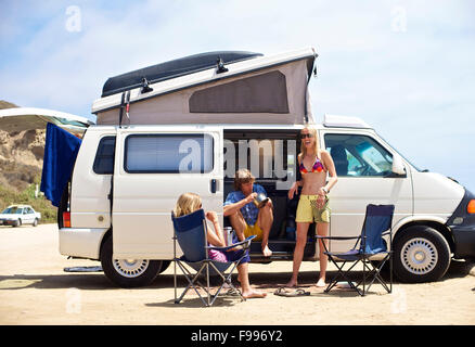 Trois personnes se tiennent à côté de leur van Camping Surf Beach, à San Onofre, Californie Banque D'Images