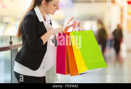 Young pregnant woman with shopping bags in shopping mall Banque D'Images