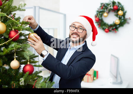 Professionnels office worker à Santa cap décoratifs suspendus bulles sur arbre de Noël Banque D'Images