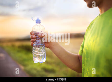 Ski de fond homme courant d'avoir de l'eau pause au coucher du soleil Banque D'Images