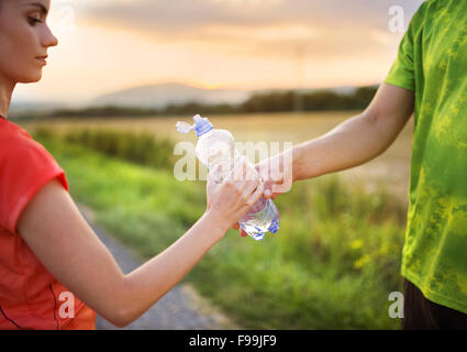 Cross-country trail running en couple d'avoir de l'eau pause au coucher du soleil Banque D'Images