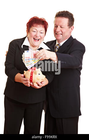 Happy senior couple mettre euro argent dans une tirelire Banque D'Images