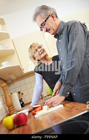 Mari la préparation des fruits pour le muesli dans la cuisine pendant qu'épouse est à regarder Banque D'Images
