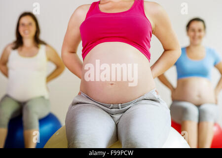Les jeunes femmes enceintes à l'aide d'un faire de l'exercice fitness ball Banque D'Images