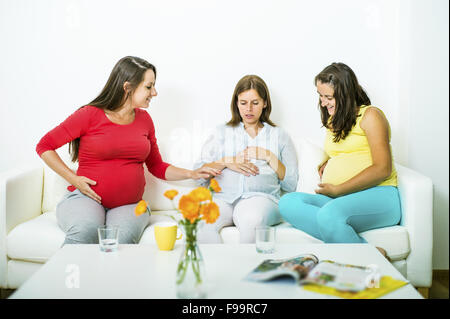 Trois femmes enceintes assis sur un canapé et le chat Banque D'Images