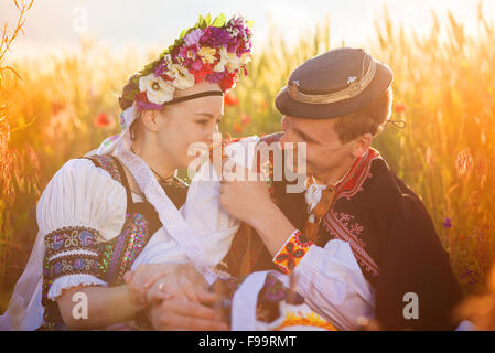 L'amour en couple coucher de champ. Ils portent des costumes traditionnels de l'Europe de l'Est. Banque D'Images