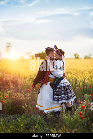 L'amour en couple coucher de champ. Ils portent des costumes traditionnels de l'Europe de l'Est. Banque D'Images