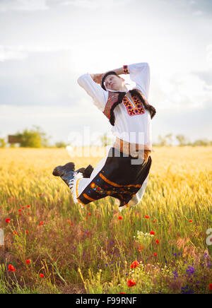 Homme saut dans le coucher du soleil. Il porte des costumes folkloriques traditionnels d'Europe orientale. Banque D'Images