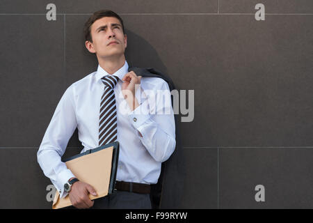 Portrait of pensive et confiant des profils d'affaires, portant costume et cravate avec documents à l'avant du mur gris avec copyspac Banque D'Images