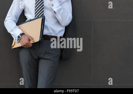 Portrait of pensive et confiant des profils d'affaires, portant costume et cravate avec documents à l'avant du mur gris avec copyspac Banque D'Images