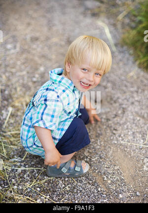 Portrait de petit garçon blond posant dehors Banque D'Images