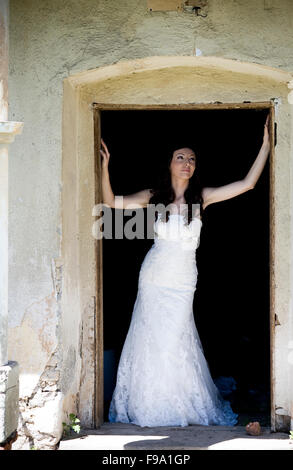 Belle et heureuse mariée brunette posing par old house Banque D'Images