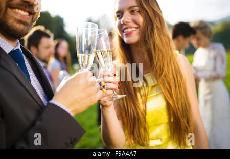 Les invités au mariage clinking glasses tandis que les mariés serrant dans l'arrière-plan Banque D'Images