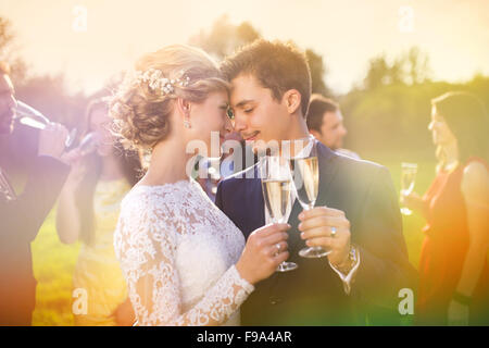 Les jeunes mariés clinking glasses et profiter de moment romantique ensemble à réception de mariage à l'extérieur Banque D'Images