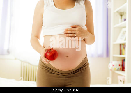 Portrait de femme enceinte méconnaissable d'une pomme dans sa main Banque D'Images