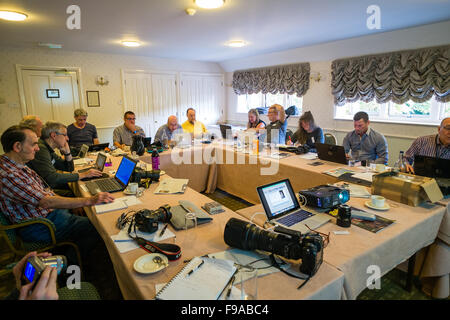 Un groupe de photographes assis autour d'une table et d'édition de photos numériques, leur traitement (faite dans le petit marché anglais ville de Cirencester) sur les ordinateurs portables dans une salle de réunion de l'hôtel lors d'un atelier d'une journée séminaire leçon classe tutoriel sur la photographie bibliothèque stock Alamy UK Banque D'Images