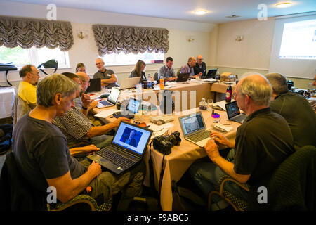 Un groupe de photographes assis autour d'une table et d'édition de photos numériques, leur traitement (faite dans le petit marché anglais ville de Cirencester) sur les ordinateurs portables dans une salle de réunion de l'hôtel lors d'un atelier d'une journée séminaire leçon classe tutoriel sur la photographie bibliothèque stock Alamy UK Banque D'Images