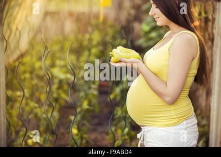 Portrait plein air de beautiful pregnant woman holding green pepper dans le jardin Banque D'Images