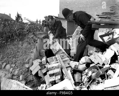 Un policier et de l'air directeur vérification des précautions Raid survivants dans un abri Anderson à Coventry blitz allemand suivants de la ville 1940 Banque D'Images