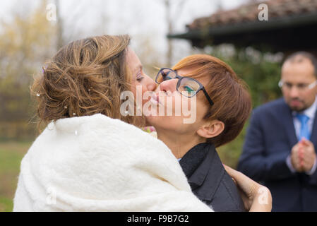 Meilleur ami embrasser, féliciter la mariée lors de la cérémonie de mariage. Le marié n'est pas mise au point en arrière-plan. Sho Banque D'Images