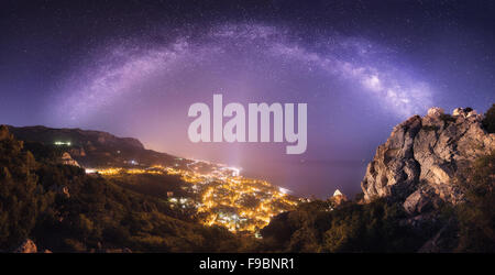 Belle nuit paysage avec voie lactée contre les lumières de la ville, les montagnes, la mer et le ciel étoilé. Nature fond Banque D'Images