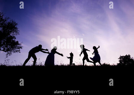 Silhouettes d'heureux parents d'avoir du plaisir avec leurs enfants Banque D'Images