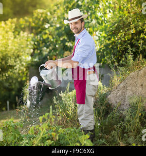 Jeune homme jardinier est d'arroser les plantes de jardin Banque D'Images