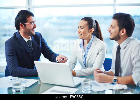 Les hommes d'affaires assis à la table et discuter de projet sur ordinateur portable Banque D'Images