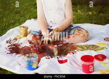 Peinture enfant mignon avec des couleurs vibrantes dans le jardin Banque D'Images