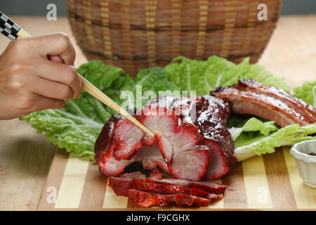 La cuisine cantonaise Char siu littéralement "fork-roast' sur une planche à découper Banque D'Images