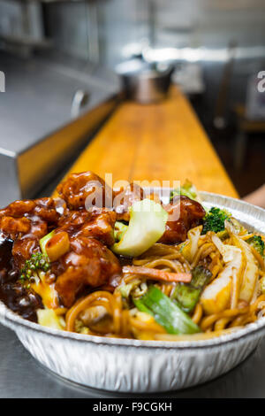 Plat populaire chinois de poulet du général tso sur la table de cuisine dans un contenant d'aluminium à emporter Banque D'Images