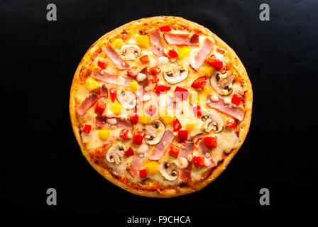 La pizza sur un fond sombre avec du jambon, champignons, fromage et piment doux vue supérieure Banque D'Images