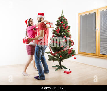 Jeune couple danse près d'arbre de Noël. Femme est enceinte.