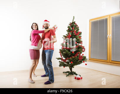 Jeune couple danse près d'arbre de Noël. Femme est enceinte. Banque D'Images