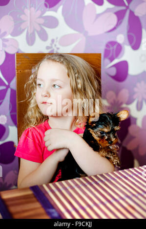 Petite fille et son chiot jouent ensemble dans la cuisine Banque D'Images