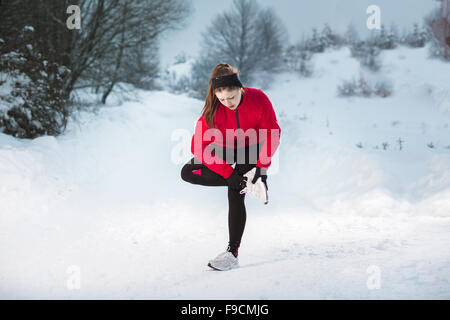 Femme de l'athlète est en cours d'exécution au cours de la formation en dehors de l'hiver dans la neige froide température. Banque D'Images