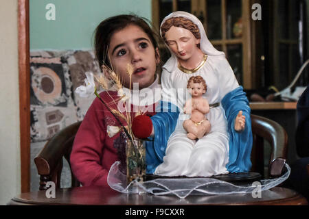 Jish, Israël. 15 Décembre, 2015. Quatre ans, Christine est membre d'une statue de la Vierge Marie et l'enfant Jésus, la décoration de l'accueil de la famille de l'AISS dans le village de Jish. Cette famille chrétienne Maronite araméen sont des descendants de réfugiés de Kafr Birim. Quelques 1 000 habitants araméen chrétien maronite ont été tenus de quitter Kafr Birim pour des raisons de sécurité en Israël de 1948 Guerre d'Indépendance avec une promesse de revenir dans un délai de deux semaines. La plupart ont trouvé refuge dans les Jish et continuer leur lutte pour revenir. Credit : Alon Nir/Alamy Live News Banque D'Images