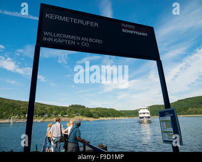 Les touristes sur les rives du lac Rursee l'attendre l'arrivée d'un navire à passagers dans le parc national de l'Eifel allemand. Banque D'Images