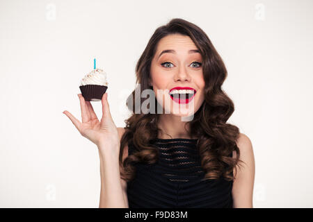 Excité attrayante jeune femme avec un miroir lumineux dans un style rétro holding birthday cake with candle Banque D'Images