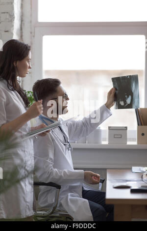 Doctors discussing intestins xray at medical office Banque D'Images