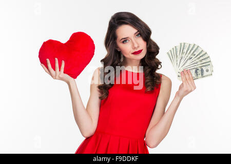 Portrait d'une belle femme en robe rouge de choisir entre l'amour ou l'argent isolé sur fond blanc Banque D'Images