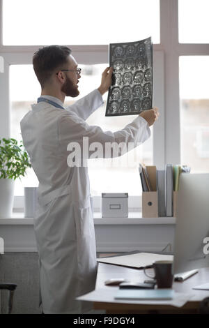 Closeup portrait of man intellectuelle avec le personnel des soins de santé, à la recherche de blanche labcoat cerveau x-ray image radiographie, tomodensitométrie Banque D'Images