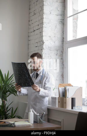 Closeup portrait of man intellectuelle avec le personnel des soins de santé, à la recherche de blanche labcoat cerveau x-ray image radiographie, tomodensitométrie Banque D'Images