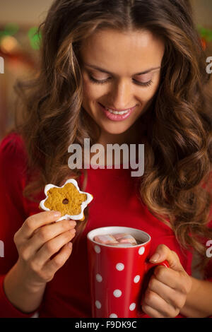 Biscuits de Noël sont une façon merveilleuse de profiter de l'esprit de la saison. Jeune femme ayant une tasse de chocolat chaud avec mars Banque D'Images