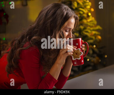 Biscuits de Noël sont une façon merveilleuse de profiter de l'esprit de la saison. Jeune femme ayant une tasse de chocolat chaud avec mars Banque D'Images