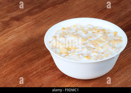 Du lait frais et des céréales dans un bol blanc sur une table en bois brown Banque D'Images