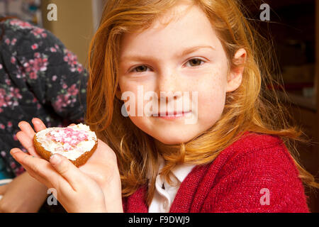 Regardez ce que j'ai fait. Une jeune fille de cinq ans tient sa création d'épices décoré avec du glaçage et des bonbons roses et blanches étoiles Banque D'Images