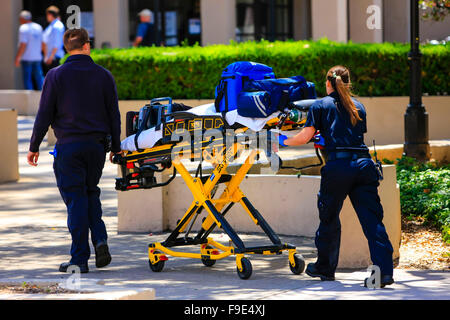 Les ambulanciers poussant une gurny chargé avec de l'équipement de sauvetage un appel au centre-ville de Santa Barbara, Californie Banque D'Images